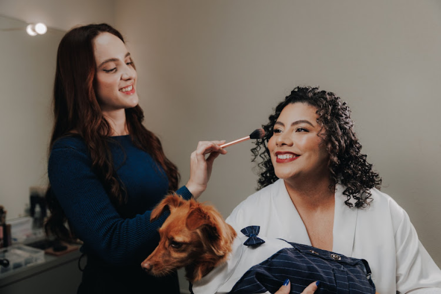 Maquiadora aplicando blush em cliente acompanhada de cachorrinho
